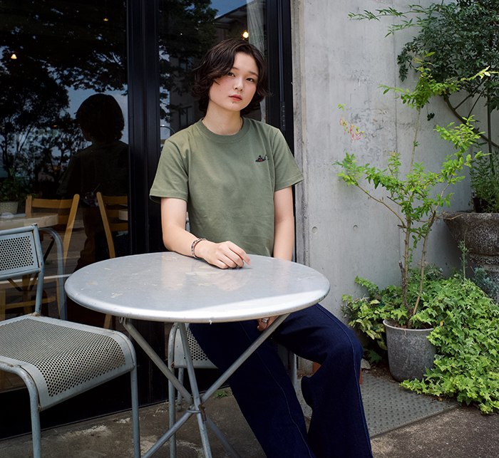 Juju選手がオリーブのTシャツを着て椅子に座っている写真サイズM