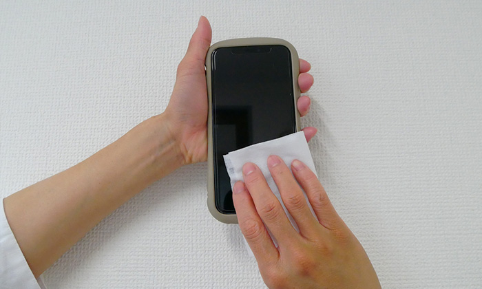 除菌シートでスマホを拭いている。