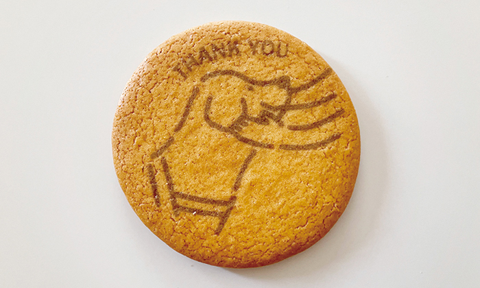 プリントクッキーの写真。ユーザーに両手で頬を撫でられ。喜んでいる盲導犬。上にはTHANK YOUの文字。