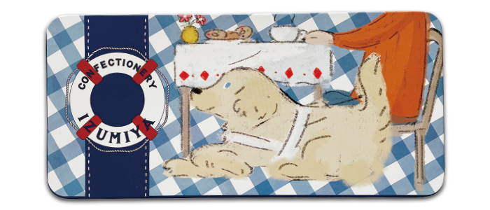 クッキー缶の写真。蓋のデザインは。テーブルに置かれたクッキーとコーヒーでティータイムを楽しむ盲導犬ユーザーと。その隣でくつろいだ様子の盲導犬が描かれている。柄は。青と白のギンガムチェック。