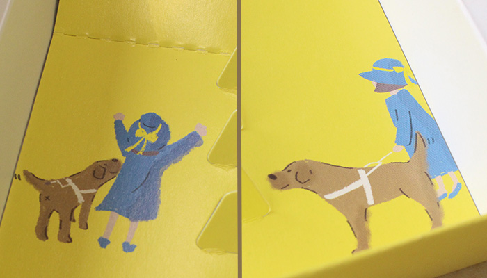 箱の中のイラスト。両側の箱下2箇所に。盲導犬と青いワンピースを着ているユーザーが描かれている。