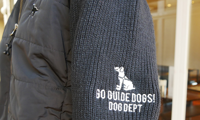 袖の刺しゅうアップ。お座りしている盲導犬の下に。Go guide dogs。DOGDEPTと書かれている。刺しゅう糸のカラーは白。