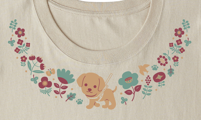 首元のプリントアップ。襟に沿うような形でプリントされている。Tシャツの真ん中に盲導犬。盲導犬の両側には。様々な種類のお花が咲いている。お花の近くには鳥や蝶々が飛んでいる。