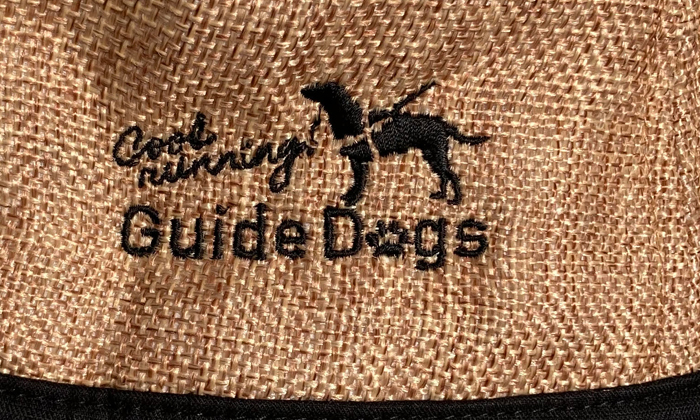 帽子の刺しゅう部分のアップ。黒い糸で。盲導犬とguide dogsの文字が刺しゅうされている。