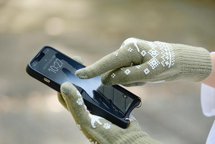 手袋をつけたままスマートフォンを操作している写真
