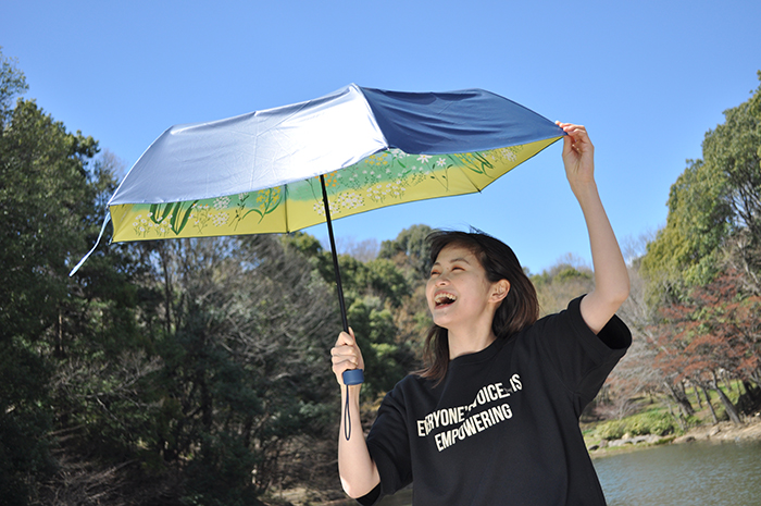 青空のもと、女性が傘をさしている写真