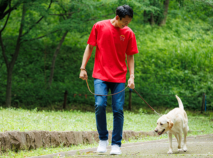 男性がレッドのTシャツを着て、ラブラドールと散歩している写真