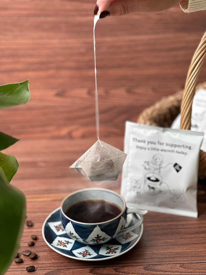 手でコーヒーバッグを吊り下げている写真