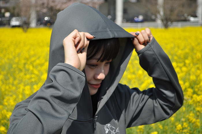 グレー着用フードを被り首元の日差しを遮る写真