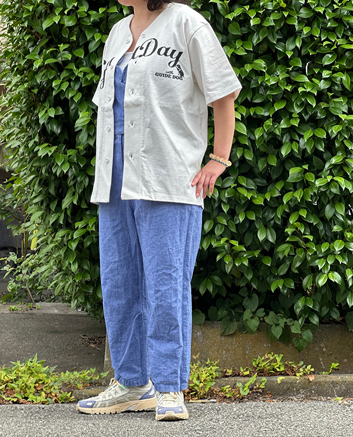 ブルーのオールインワンパンツに黒のロゴのベースボールTシャツを羽織っている写真
