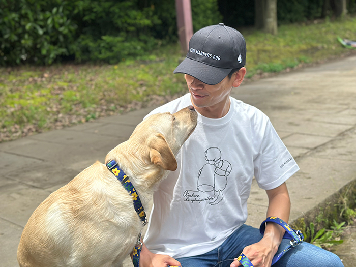 ラブラドールとキャップを被った男性が寄り添っている写真