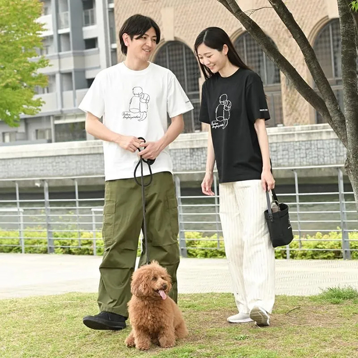 男性がホワイト女性がブラック、色違いでTシャツを着て犬の散歩をしている写真
