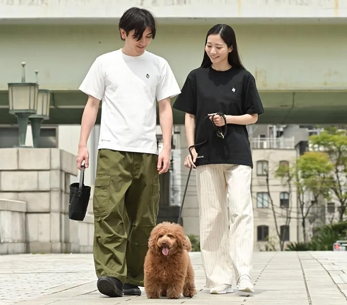 男性がホワイト女性がブラック、色違いでTシャツを着て犬の散歩をしている写真