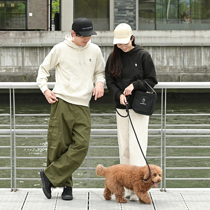 男性がオートミール、女性がブラックの色違いのフーディーを着て犬の散歩をしている写真