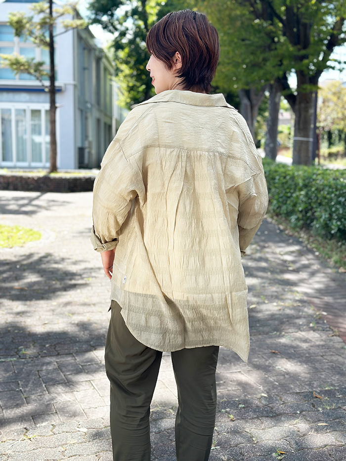 女性がベージュのシャツを着て後ろを向いている写真