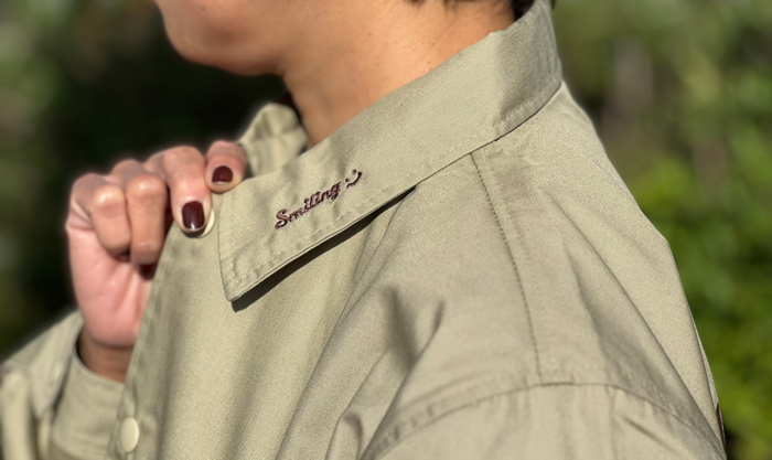 ベージュを女性が着用し、刺繍部分を手で持っている写真