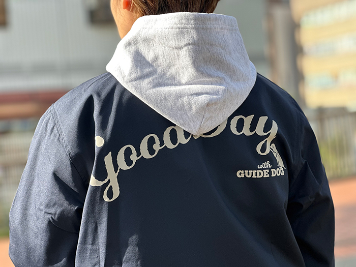 女性がネイビージャケットの中にグレーのパーカーを着用し後ろを向いている写真