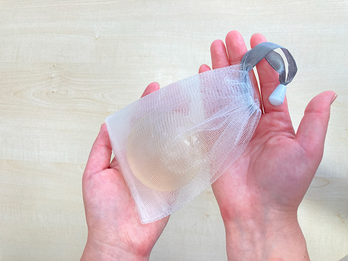 泡立てネットに石鹸を入れて両手のひらに乗せている写真