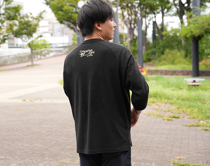 男性がバックプリントのブラックを着て背を向けている写真