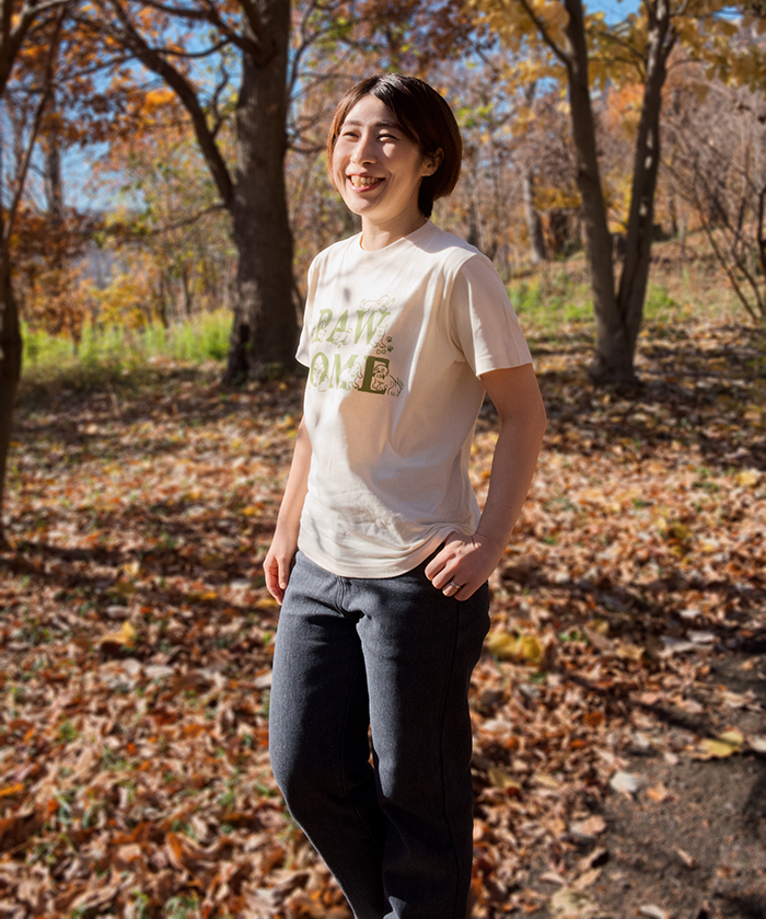 女性がアイボリーのTシャツを着用し正面を向いている写真