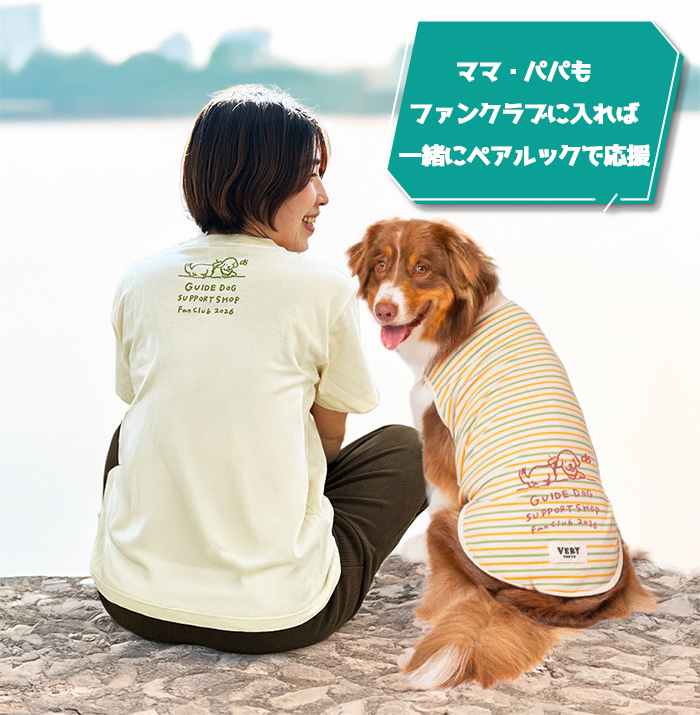 人がファンクラブTシャツを着て、横にTシャツを着た犬が座っている写真
