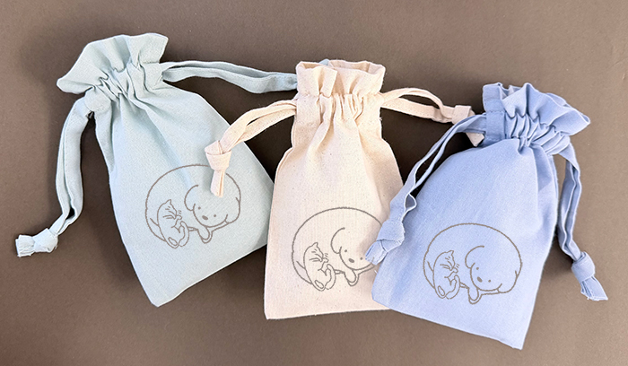 ３色の巾着が並んでいる写真。左からくすみカラーのグリーン、生成り、ブルーの巾着