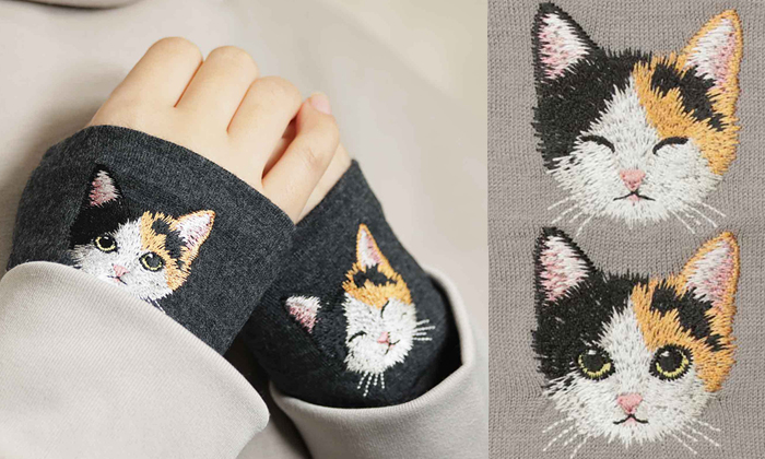 左側は女性が杢ブラック生地に三毛猫の刺繍がされているハンドマフラーを着けている写真。右側はサンドベージュに三毛猫が正面を向いて目をつむり笑っているような表情と、刺?墸の写真
