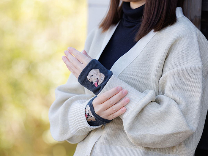 女性が白いセーターの下に杢ブラックの手袋をつけた写真