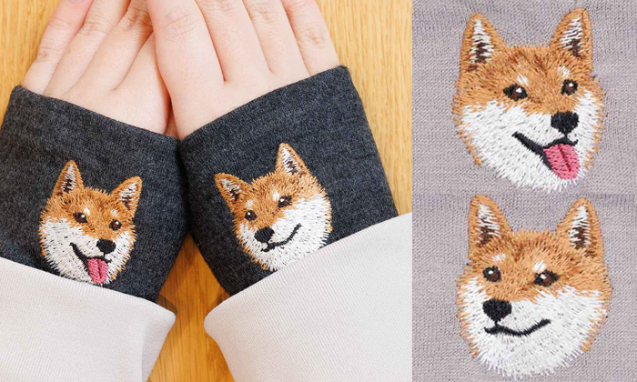 左側は女性が杢ブラック生地にシバのレッドの刺繍がされているハンドマフラーを着けている写真。右側はサンドベージュにシバのレッドが左右斜め横を向いている刺?墸の写真