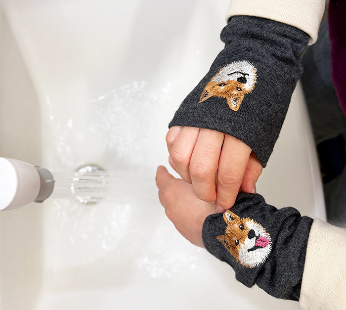 作業をした後に、まくり上げたハンドマフラーを手首の位置に戻している写真