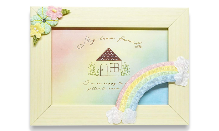 フォトフレームの左上にはブルー黄色ピンクの花が。右下には雲から虹がかっているちりめん細工が付いている