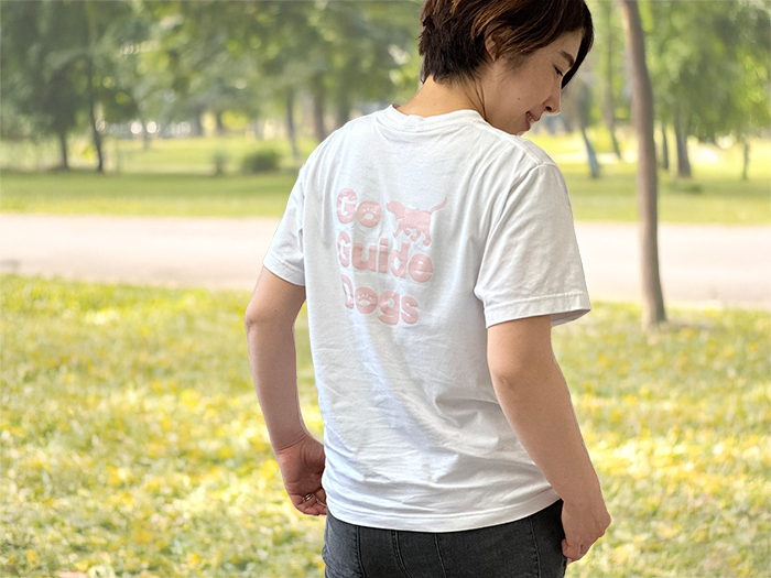 女性が外でホワイトにダスティピンクのプリントのTシャツを着ている写真