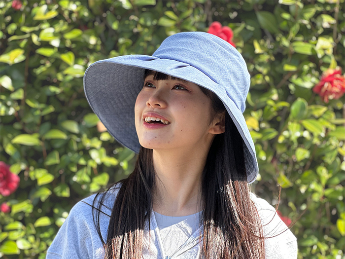 女性が涼し気な色のタックキャペリンの帽子を被っている写真。