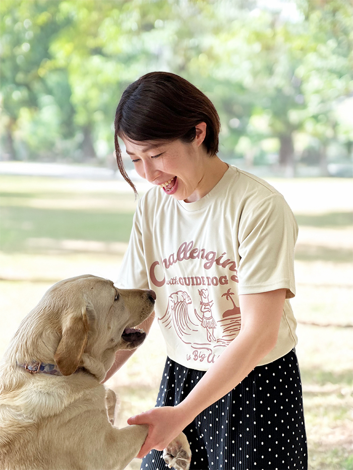 フラ犬のドライTを着用しラブラドールの両手を持っていて二人とも笑顔な写真