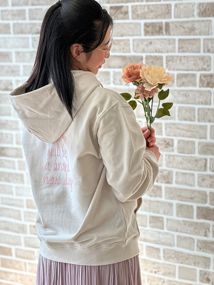 女性がグレージュのパーカーを着て、花束を手に持っている写真
