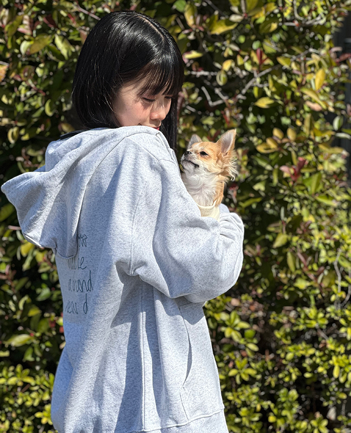 女性がアッシュのパーカーを着て、チワワを腕に抱いている写真