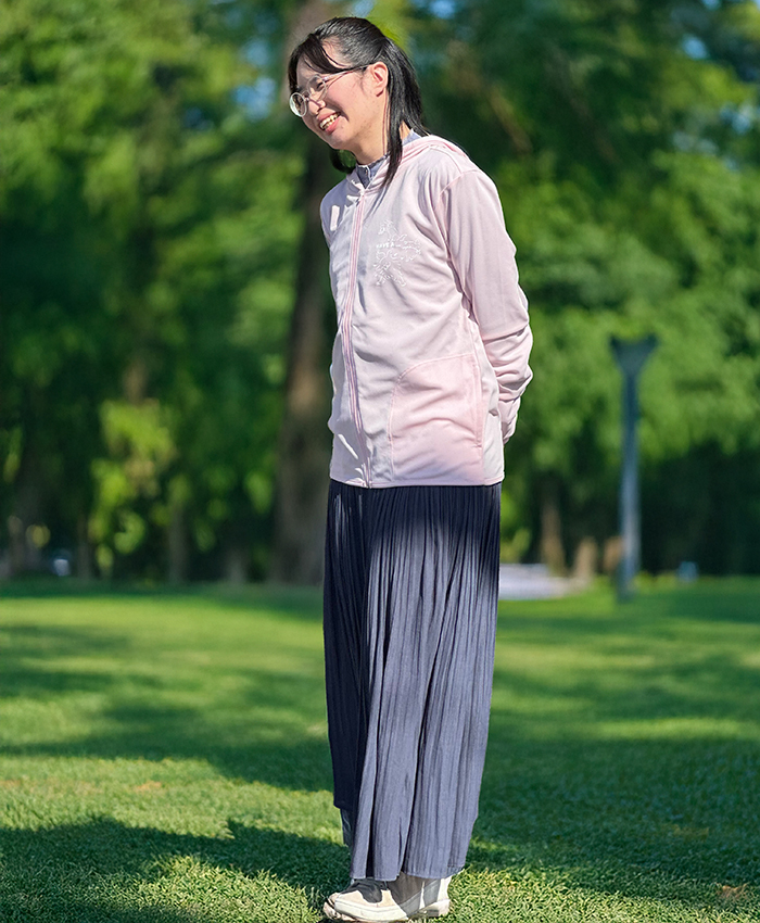 ライトピンクのパーカーにグレーのロングスカートを着用している写真