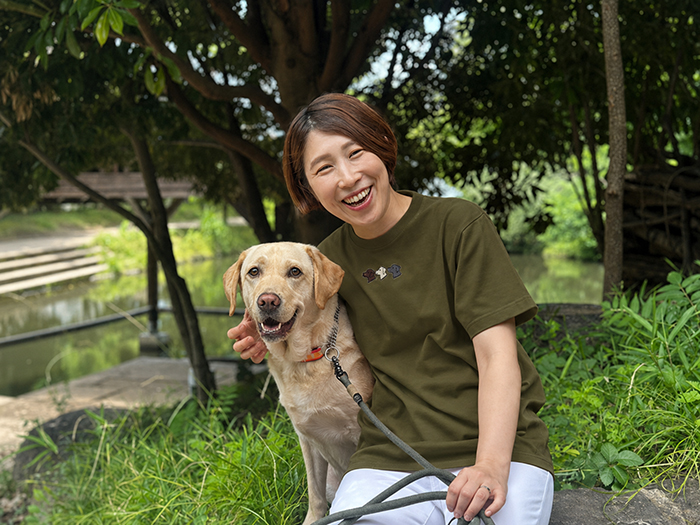 女性とラブラドールがしゃがみ揃って笑顔の写真