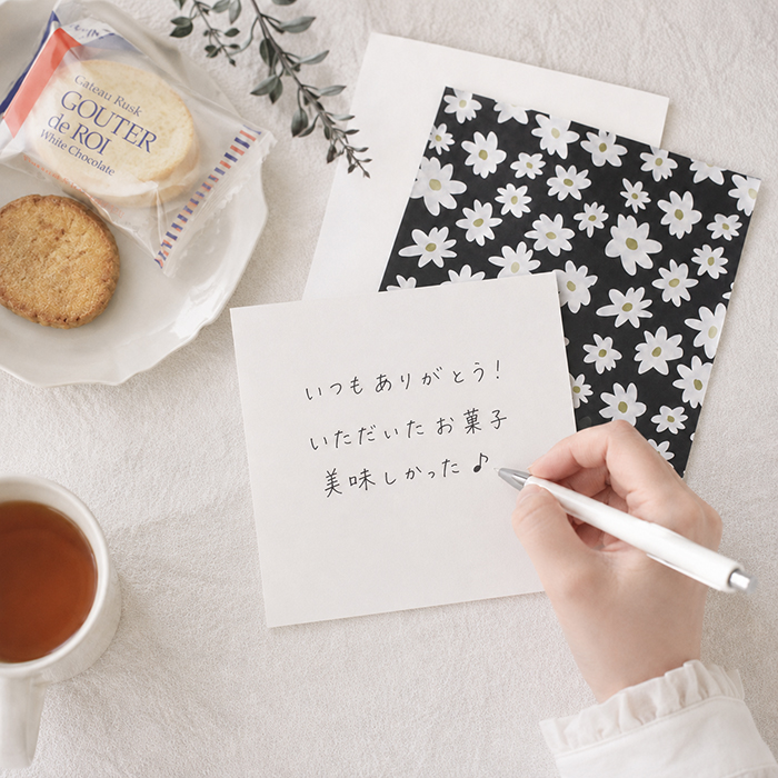 テーブルの上でカードの裏にメッセージを書いている写真