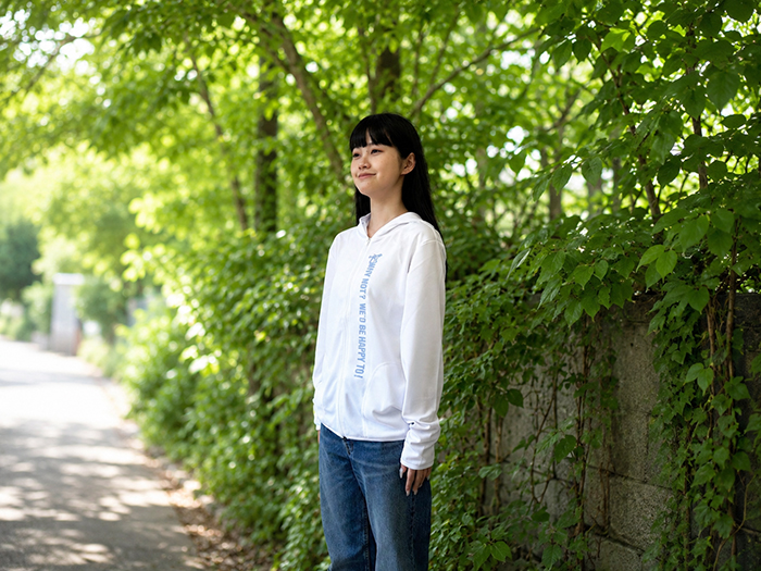 女性がホワイトのパーカーにボトムはデニムを着用している写真